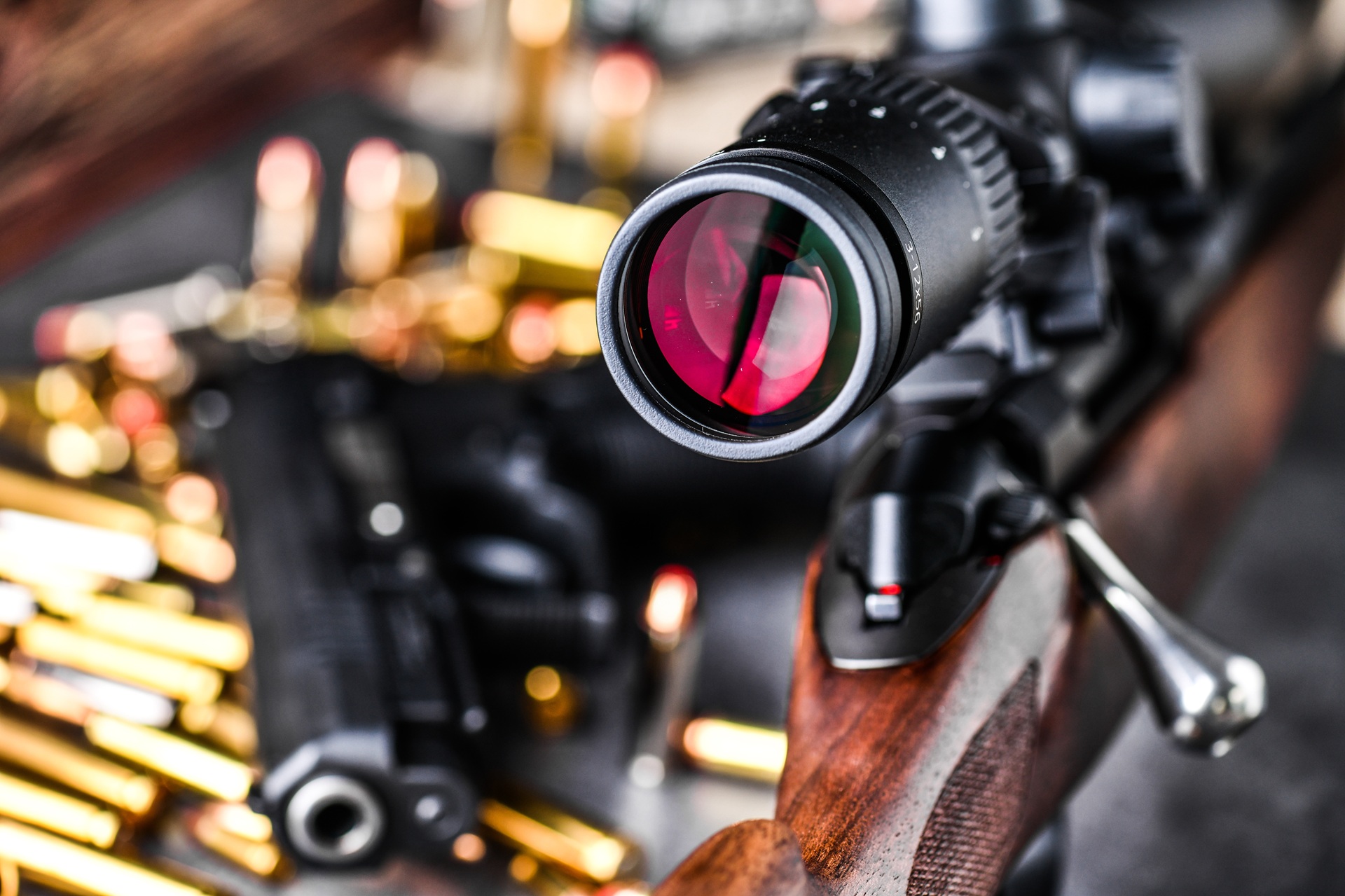 Image of a rifle with a scope ewith ammunition in the background